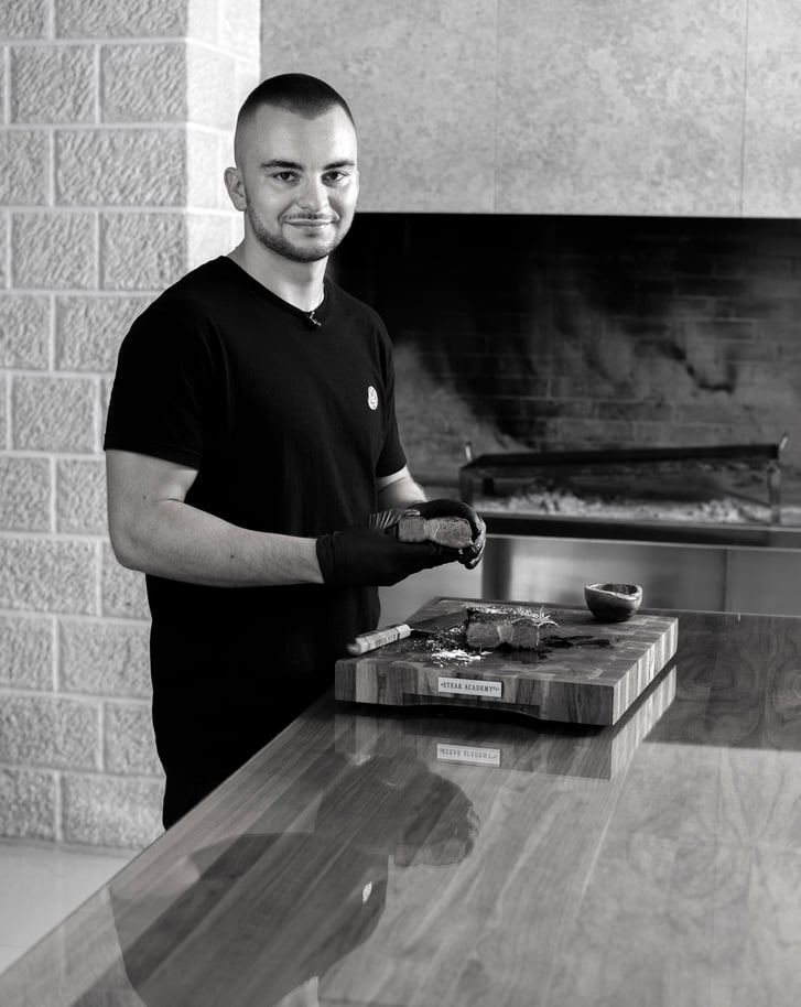 Ivan Đukić standing in a kitchen with a cutting board and knife